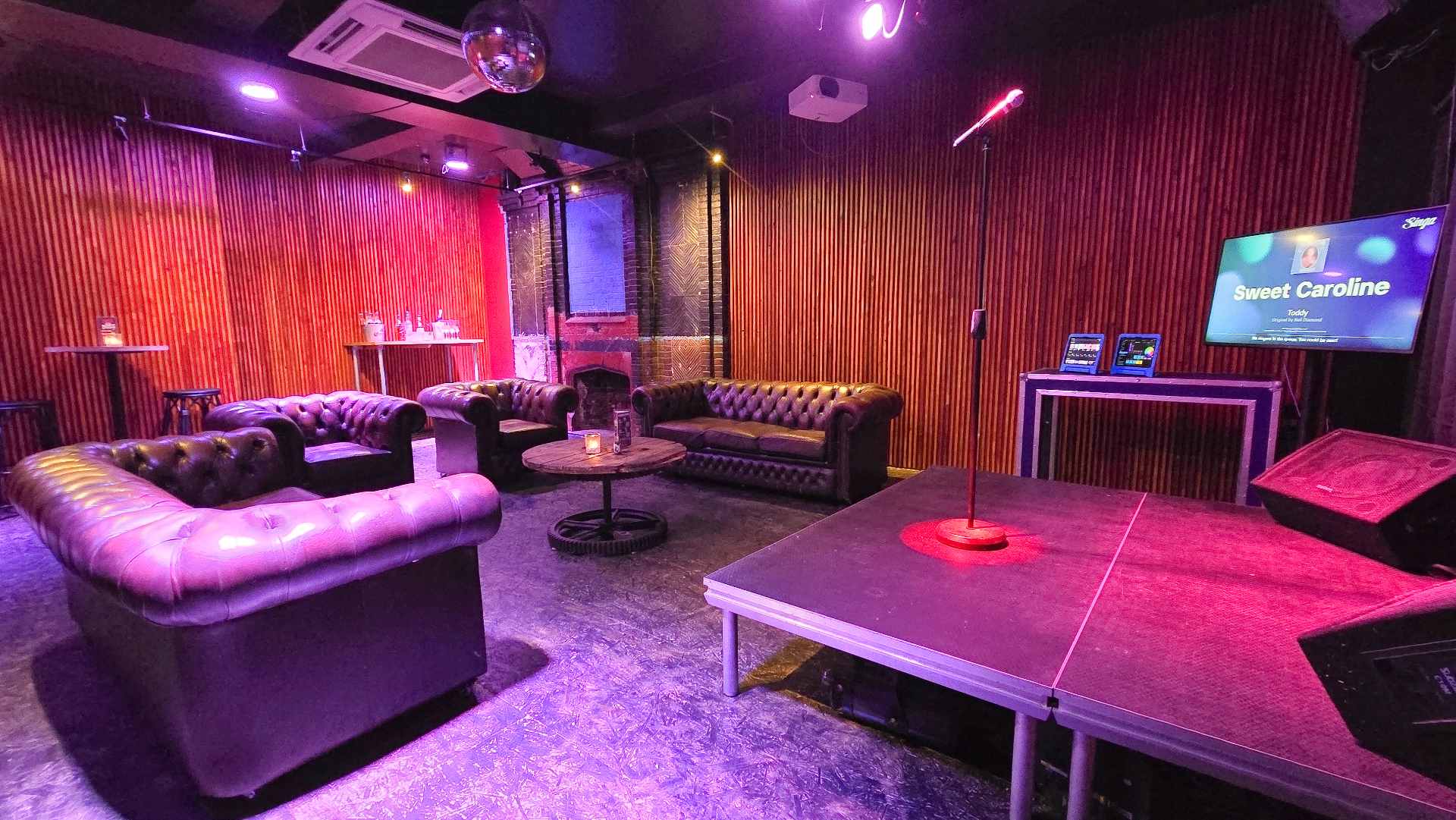 Karaoke room with disco ball and Sweet Caroline on screen